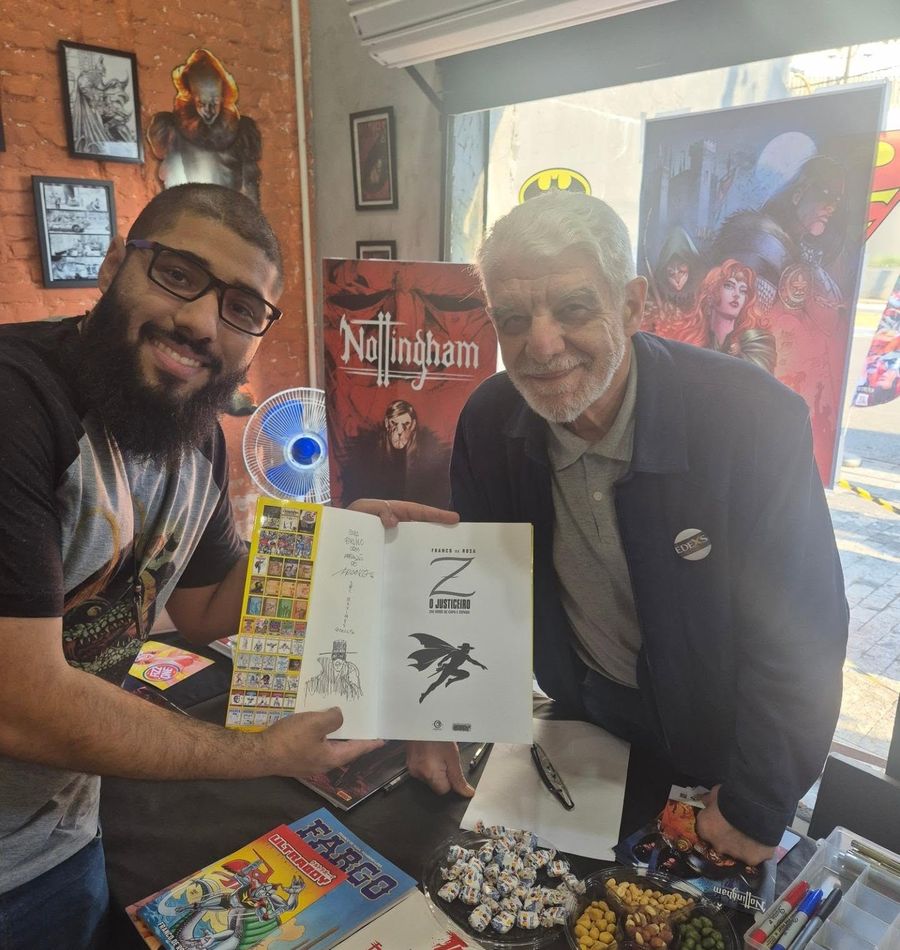 Artista autografando um quadrinho para um leitor na mesa da loja